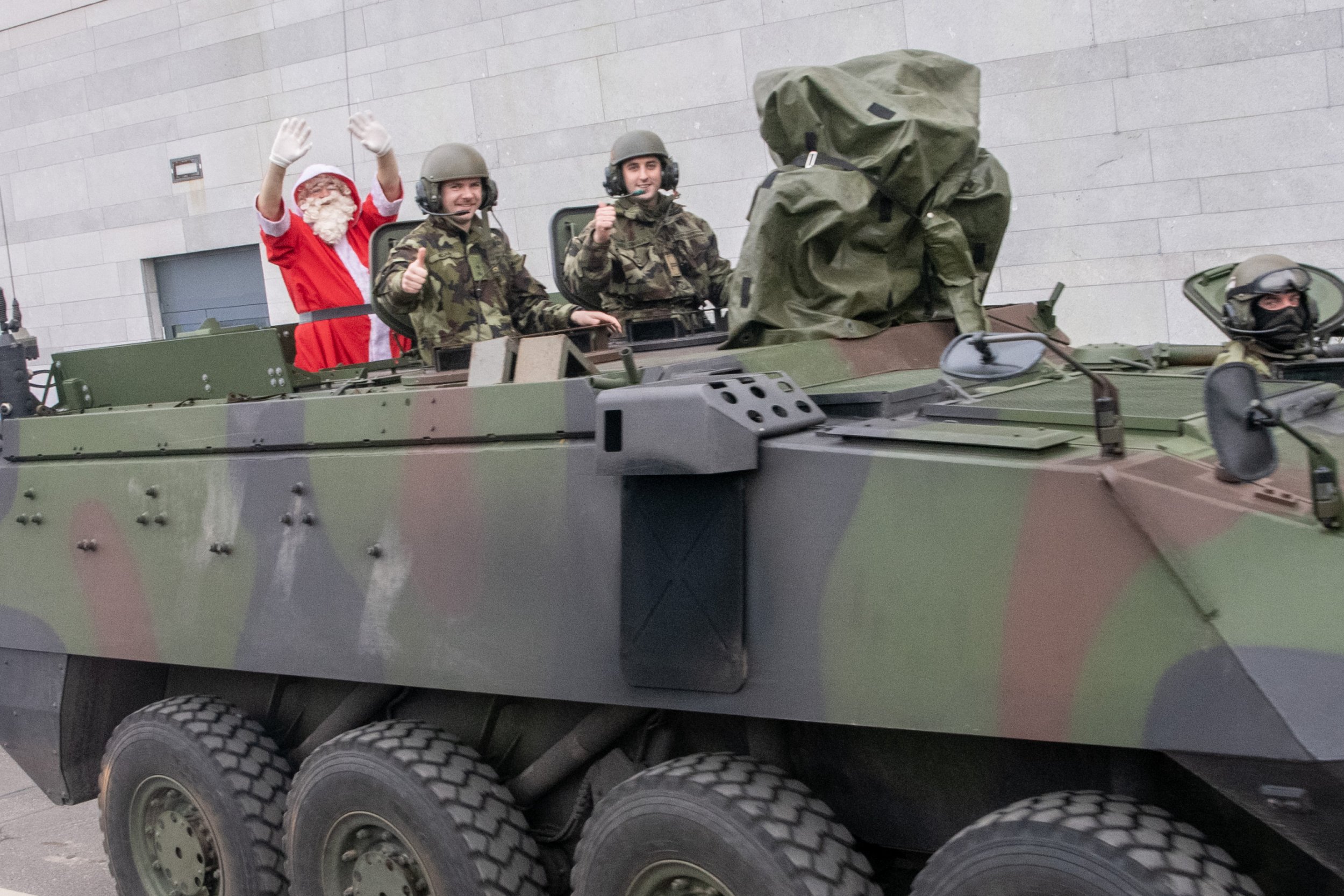 Santa waving from the top of an Irish Army armoured vehicle, with two soldiers giving thumbs-up