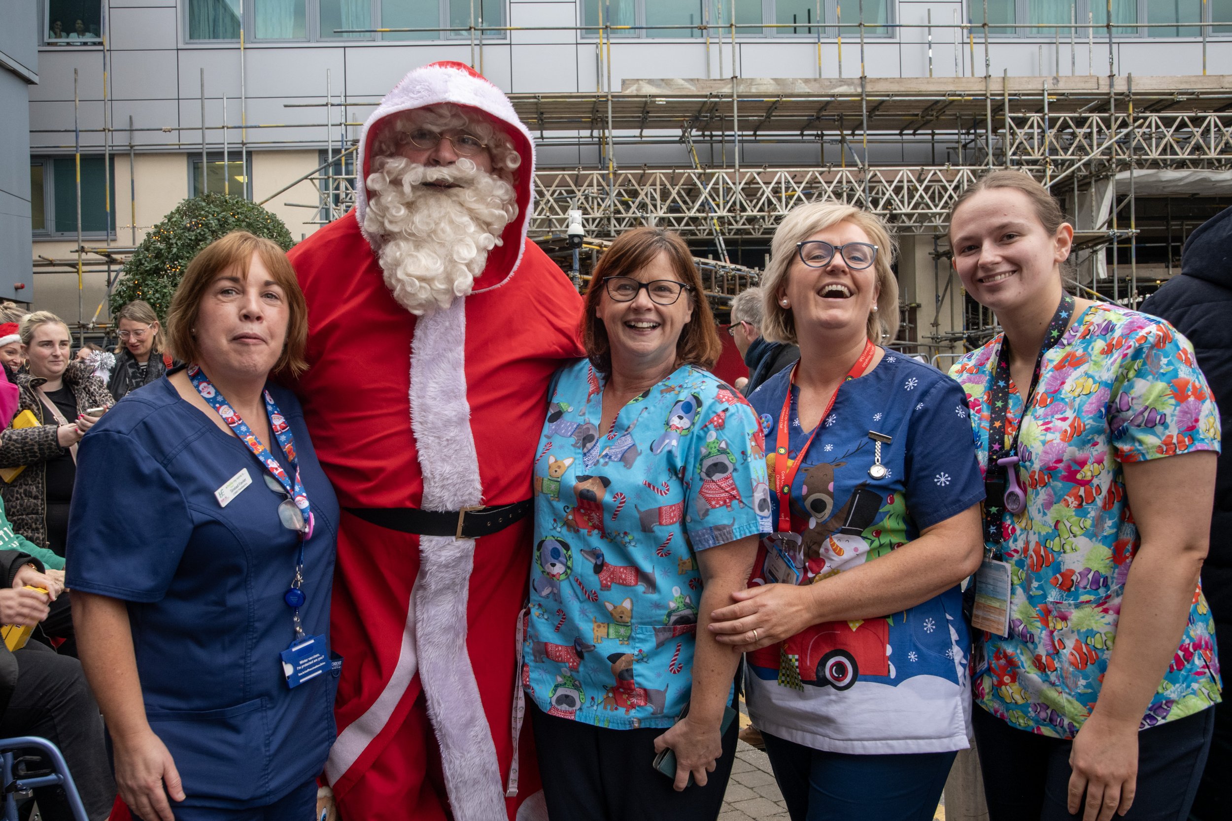 Santa Claus posing with four hospital nurses in colourful scrubs outdoors